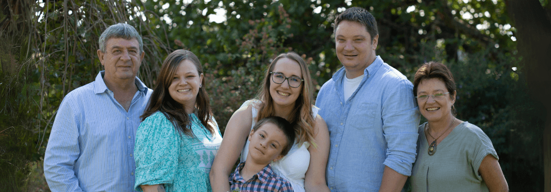 A picture of a multi generational family looking at the camera with trees and nature in the background