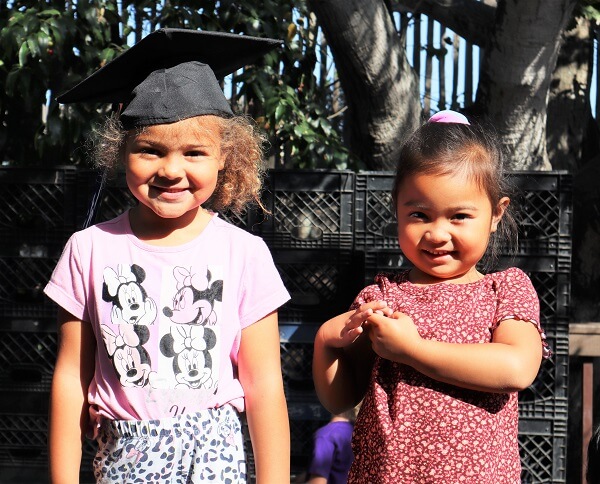 Two preschool kids with graduation hats on