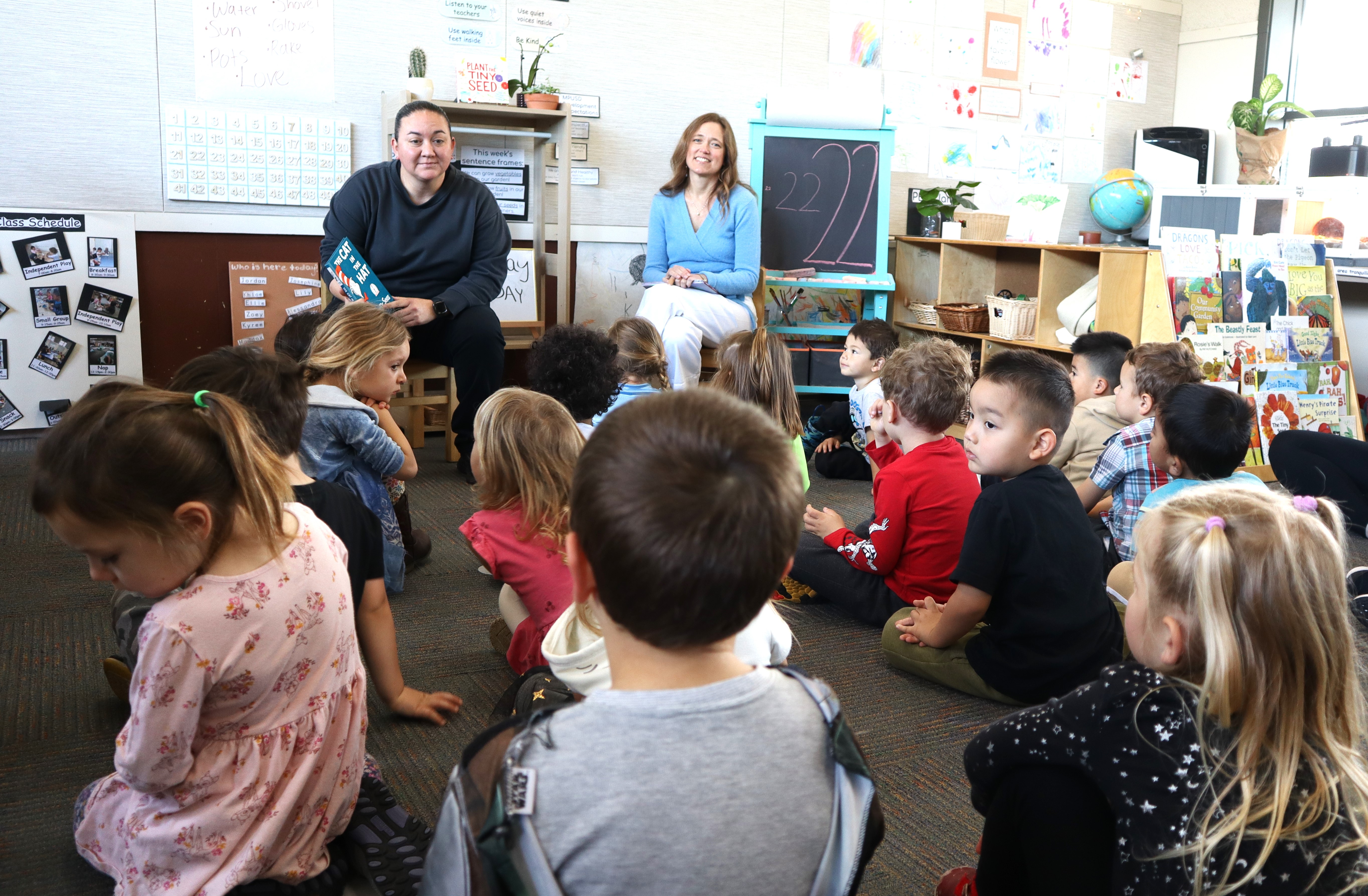 Twoo volunteers reading to kids sitting on the ground