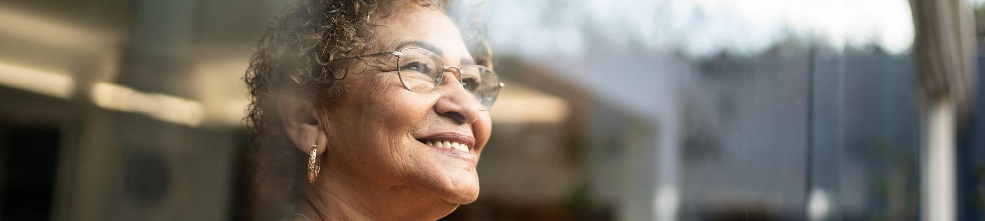 Older woman looking out a window smiling